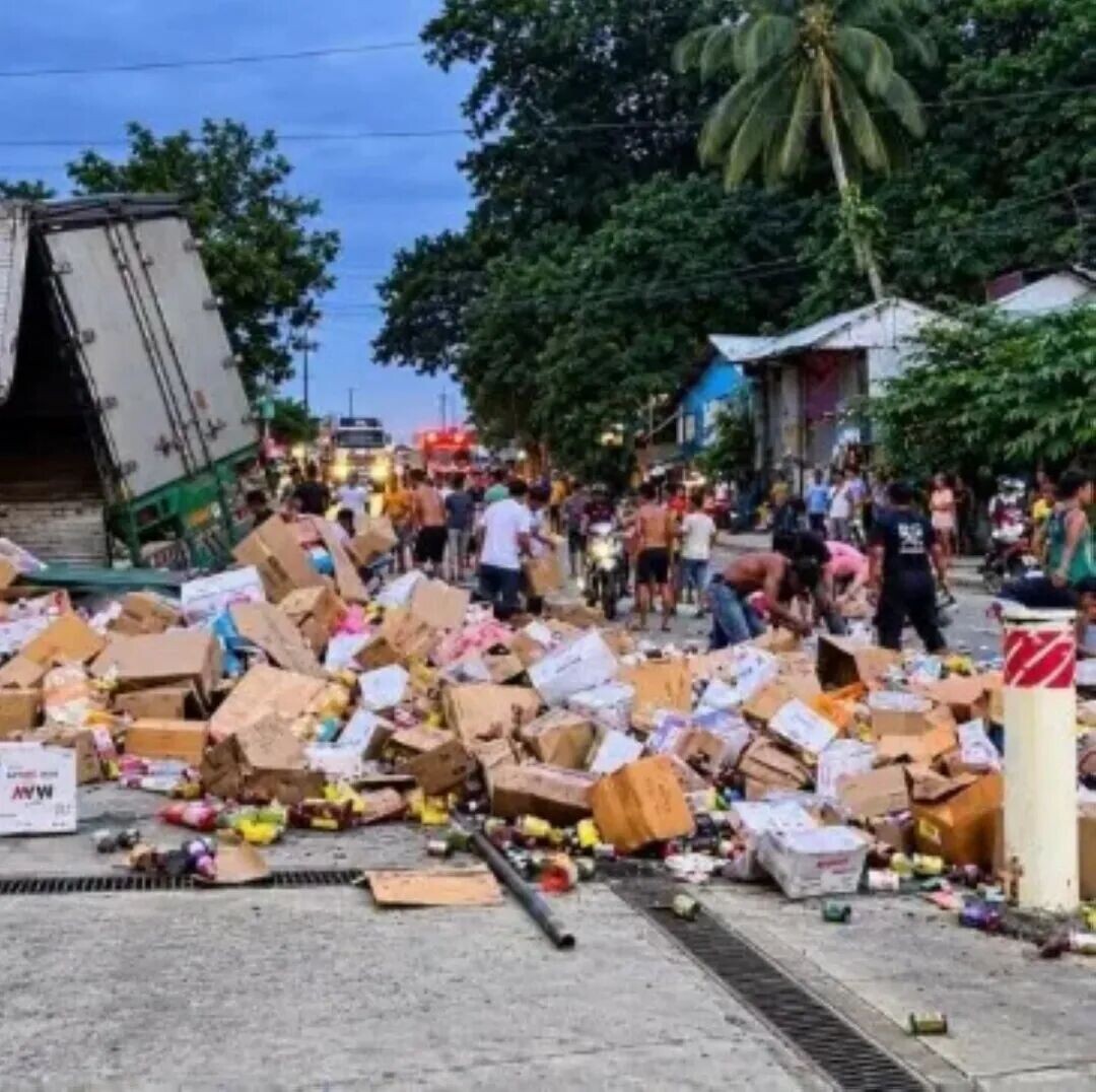 Residents grab boxes of groceries from a truck that crashed in Barangay Angeles, Atimonan, Quezon, on Sunday, Sept. 27. (Photo via Danny Estacio)